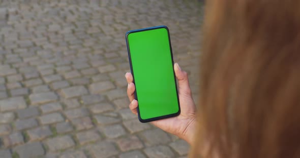 Crop View of Female Person Holding Mockup Screen Smartphone While Walking at City Street with Paving