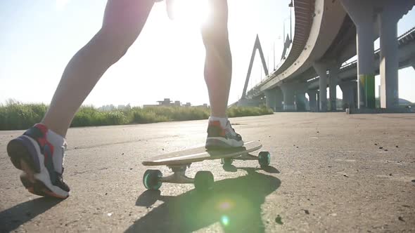 Young Woman with Nice Legs Riding Skateboard Outside - Bright Sunlight
