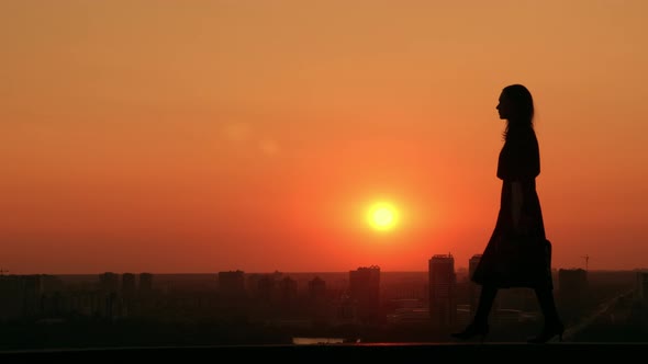 Woman Walking Outdoors Cityscape at Sunrise Dawn in Town