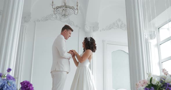 Bride and Groom Hold Hands and Look Each Other in the Eye