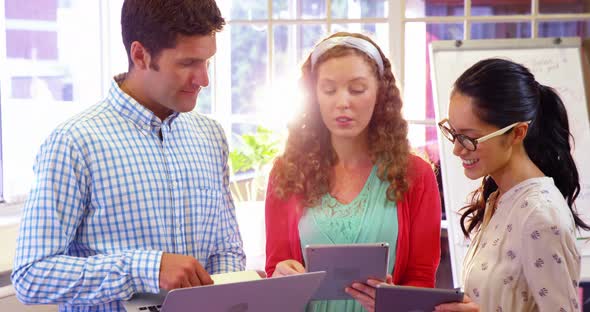 Group of business executives interacting over digital tablet and laptop