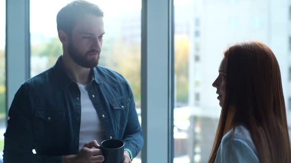 Closeup of Male and Female Office Workers Standing on Background of Window in Office Meeting and