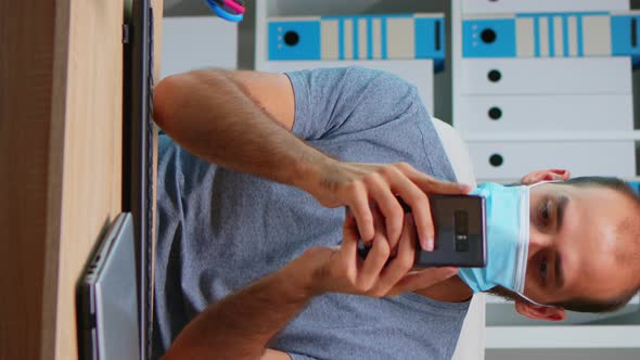 Vertical Video: Office Worker with Mask Using Phone