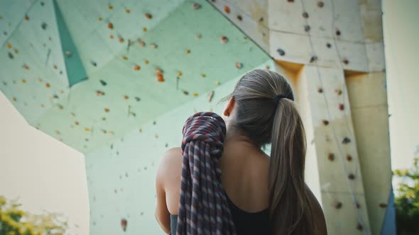 Back View on Young Sporty Girl with Climbing Rope Looking at Artificial Rock