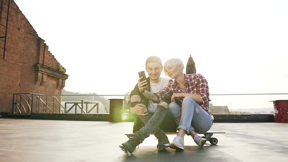 Young Hipster Couple are Sitting on Longboard Skateboard