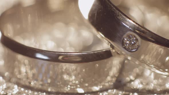 Wedding Gols Rings Lying on Shiny Glossy Surface. Shining with Light. Close-up