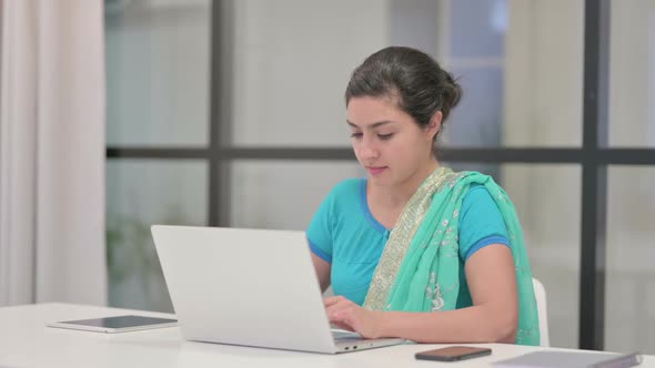 Indian Woman Looking at Camera While Using Laptop in Office