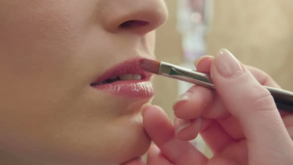 Makeup Artist Uses Brush To Apply Lip Gloss To Model Lips