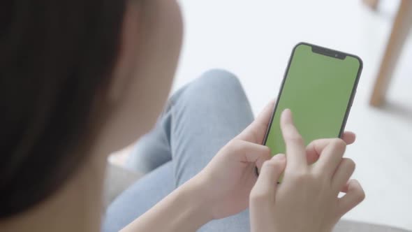 Young asian woman holding hand and watching using smart phone with green screen.