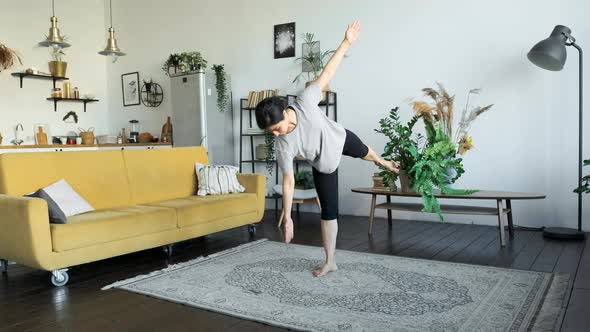 A Young Indian Woman Does Yoga Meditation At Home, Does A Balance Exercise, Stands On One Leg