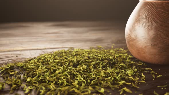 Yerba mate in gourd. Calabash with bombilla next to the pile of shredded leaves.