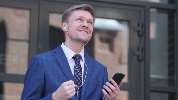 Dancing Businessman Listening Music on Smartphone