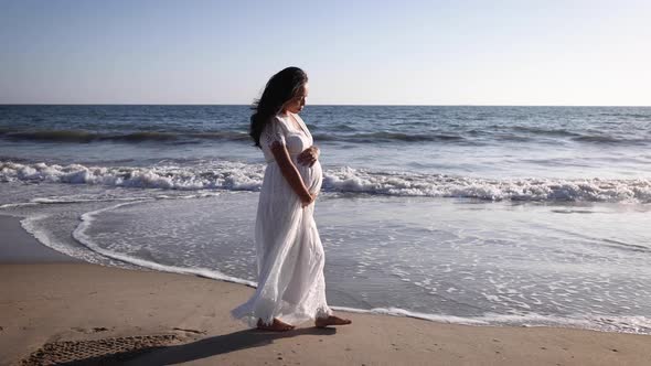 Pregnant Asian woman enjoying walk on the beach