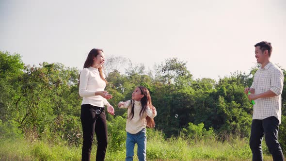 happy family life concept. Asian parents and the little girl enjoying and fun playing soap bubbles.