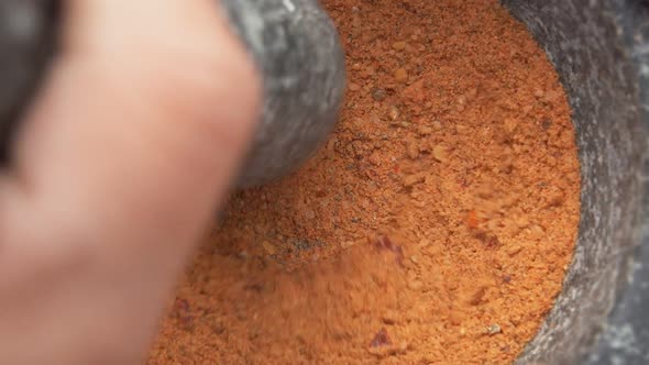 Super Closeup of Heavy Pestle Grinding and Mixing Spices in a Grey Stone Mortar