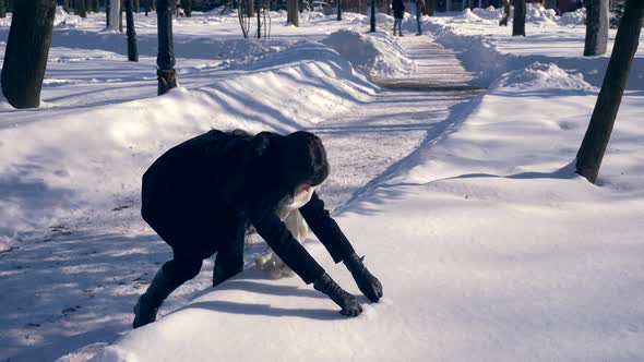 Pretty Brunette Girl Draws Heart On Snow. Sunny Day In Winter City Park Slow