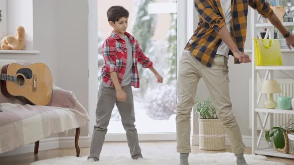 Wide Shot of Confident Funny Middle Eastern Boy Dancing with Unrecognizable Teenage Brother at Home