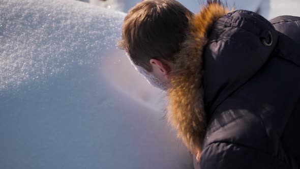 A Man in a Winter Jacket Makes an Imprint of His Face in a Snowdrift