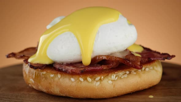 Egg Benedict. Pouring French Hollandaise sauce on poached egg.