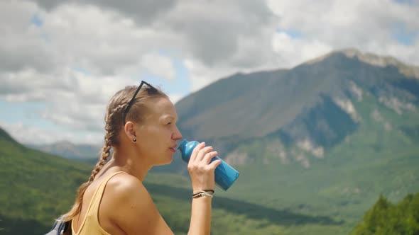 A Young Sporty Woman Drinks Water on a Bright Sunny Day