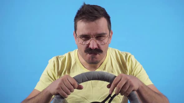 Focused Man with a Mustache Behind the Wheel on a Blue Background Slow Mo Isolate