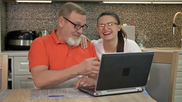 Beautiful Young Woman Is Explaining To Her Elderly Father How To Shop and Various Payments Online