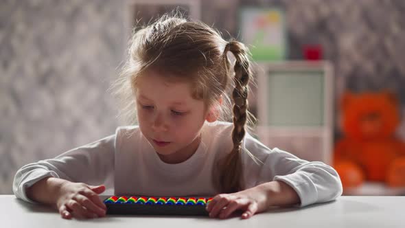 Tranquil Girl with Abacus Solves Tasks Sitting at Workplace