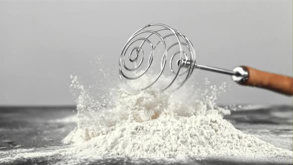 Super Slow Motion Whisk Falls on the Table in a Pile of Flour