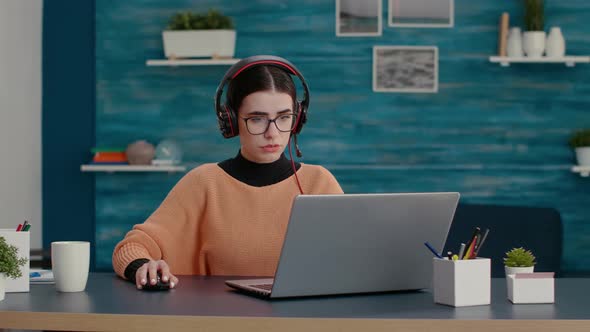 University Student Using Headphones and Laptop to Attend Online Class alt