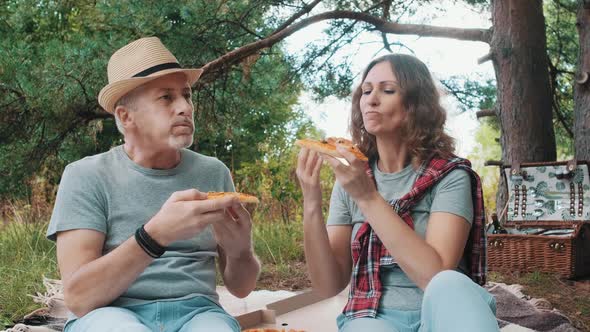 A Married Couple Eat Pizza and Relax in Nature Sitting in the Woods for a Picnic on a Summer Day