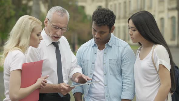 Senior Teacher Showing New Educational App on Tablet to Students, MBI Studies