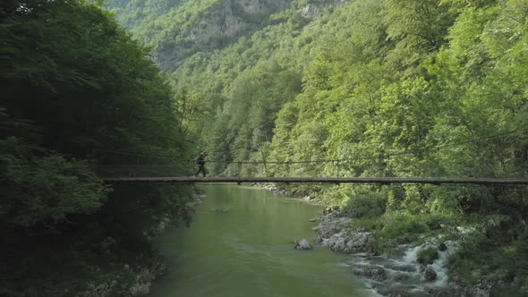 Aerial view of woman traveler walking on the bridge under Tara river in Montenegro