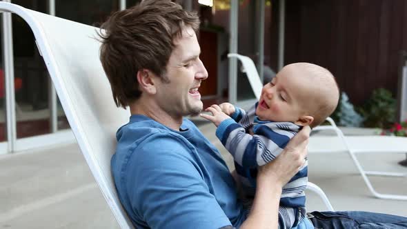 Father and baby son on lounge chair, playing