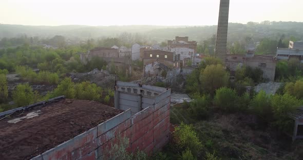 Abandoned industrial factory building overgrown with grass and trees