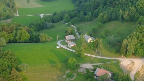 Old family houses with barns up in hills surrounded with meadows and green spruce trees. Aerial 4k v