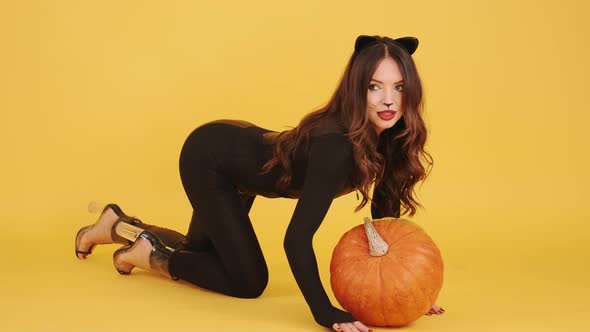 Woman in Halloween Makeup Holding Pumpking on Orange Background