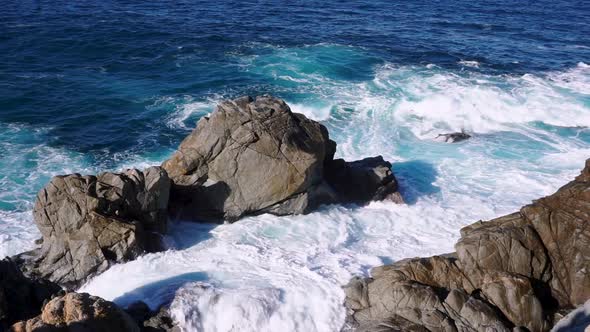 Gentle but powerful waves of the Pacific Ocean washing against rocks on the cost of Big Sur, Califor