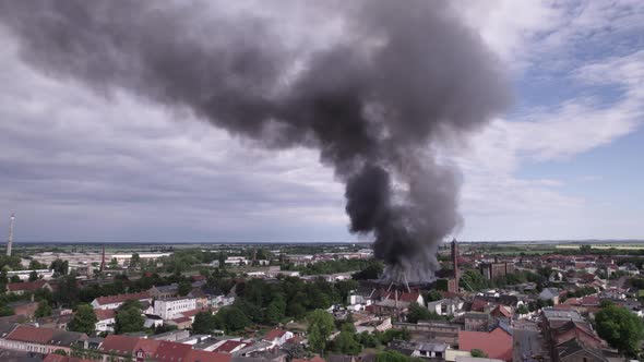 Static aerial shot of building roof burning with black smoke in Kothen Germany