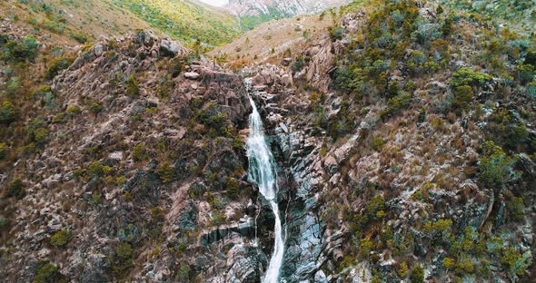 Aerial shot of a waterfall in Tasmania. Shot slowly drops with the flow of water.