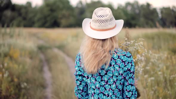 Female Sniffs Bouquet Of Wildflowers. Girl Collects Daisies On Field. Romantic Girl Gathering Flower