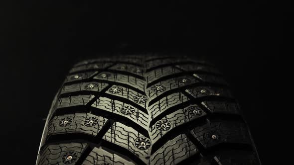 Car Winter Tire with Studded on Black Background