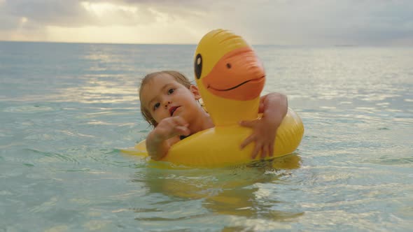 Adorable Baby Girl Swimming with Inflatable Duck in Indian Ocean