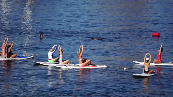 Group of Young Womens in Swimsuits Doing Yoga and Pilates on Sup Board in Calm Sea Early Morning