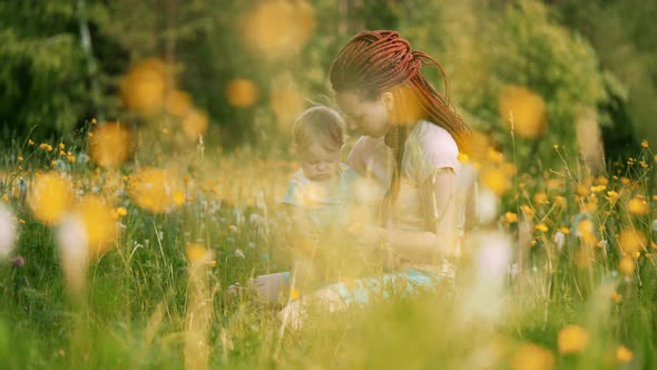 Mom with a child are sitting in a clearing or park. Parenting Maternity Joy Family Concept. alt