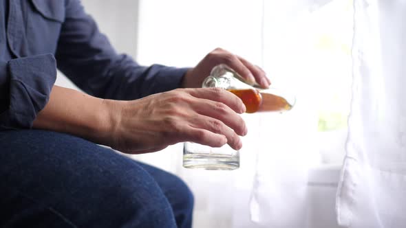 Alcoholic man with glass in hand pouring alcohol with tremors