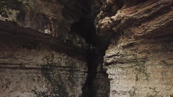 Aerial View of the Man Holding a Rope and Descending Into the Cave