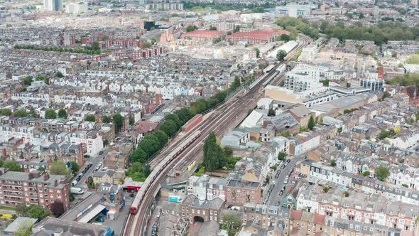 Follow drone shot of London underground train arriving at parsons green station