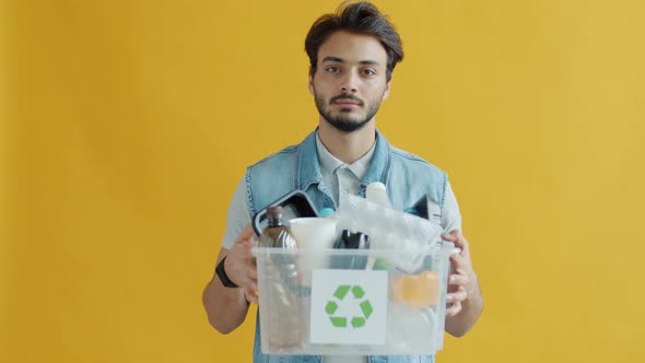 Portrait of Indian Man Holding Box of Plastic Waste for Recycling and Looking at Camera