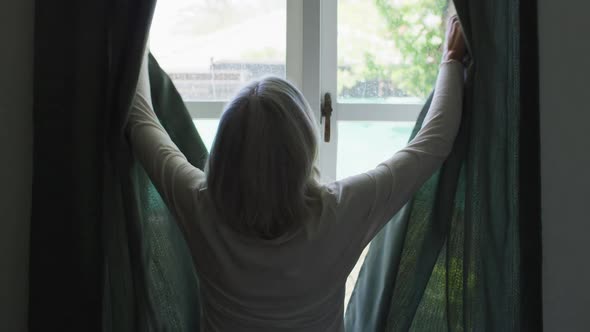 Rear view of senior caucasian woman at home standing at a window