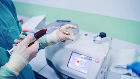 Stem cell research. Laboratory worker holding syringe with blood near the modern equipment.